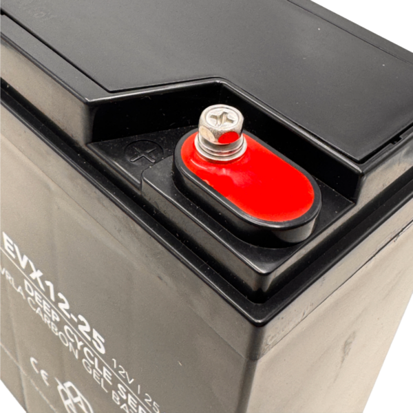 Im Vordergrund steht ein Landport EVX 12V 25Ah Akku aus einem Fünfer Akkusatz. Die Nahaufnahme zeigt die obere Ecke des Akkus mit einem rot markierten Polanschluss und einer silberfarbenen Schraube. Das Gehäuse ist dunkel und trägt weiße Beschriftung, die teilweise lesbar ist. Die Oberfläche wirkt glatt und robust.
